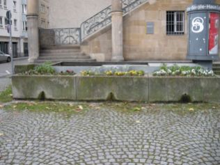 Treppenabgang zum Bunker unter dem Leonhardsplatz vor dem Gustav-Siegle-Haus. Bepflanzte Betontröge und Sitze sollen die Metallverkleidungen in den Platz zu integrieren.
